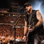 Brantley Gilbert’s live concert coverage featuring a country rock singer playing guitar on stage before a packed crowd.