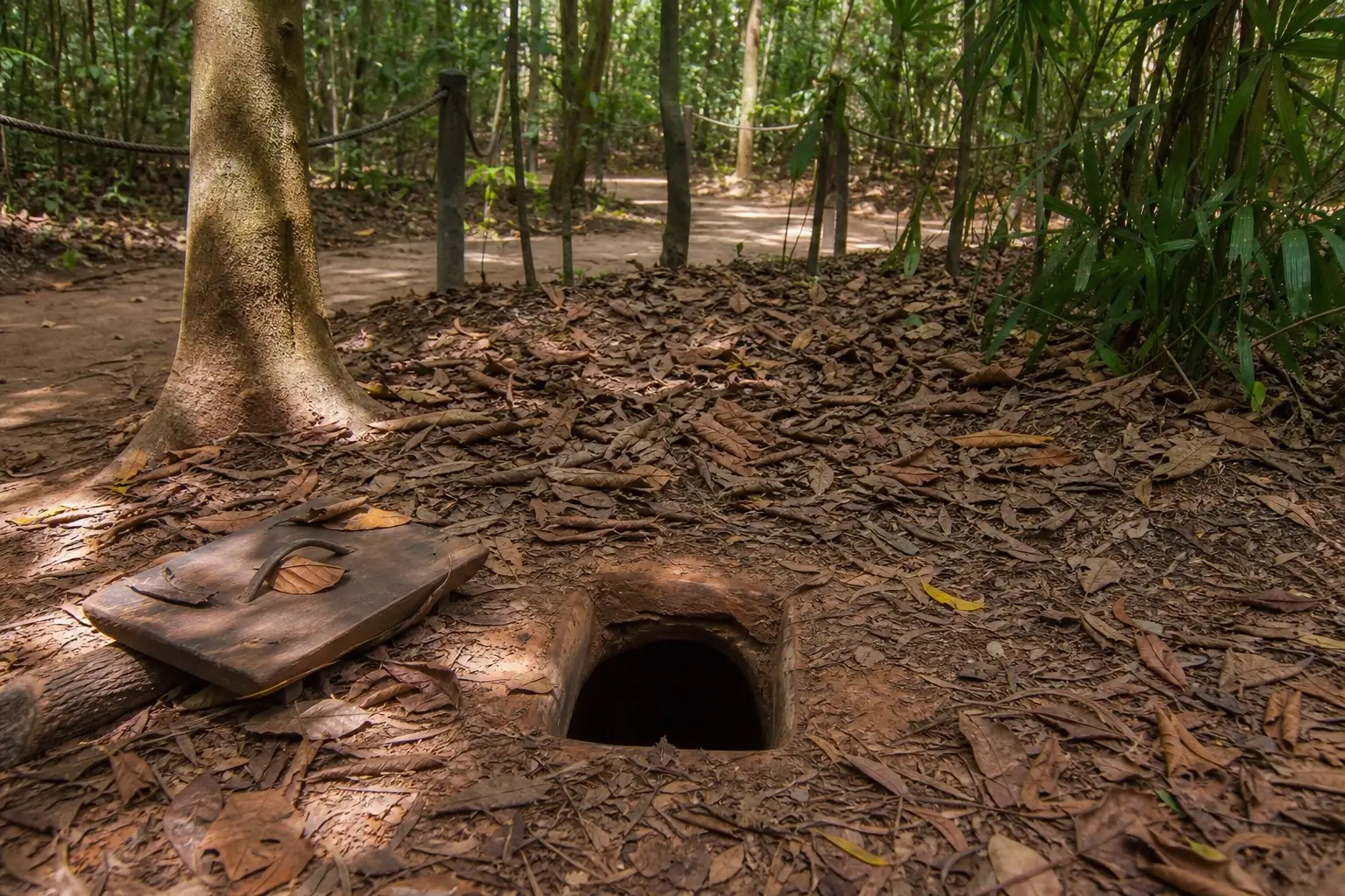 Cu Chi Tunnels entrance hidden in forest floor near Ho Chi Minh City, Vietnam