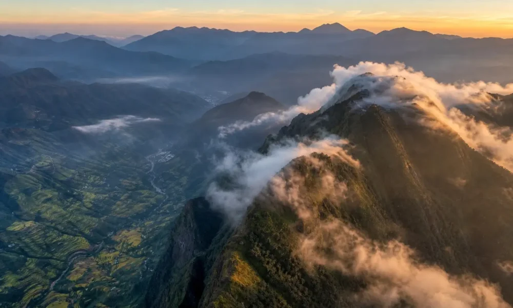 Aerial view of Fansipan summit above clouds and Sapa rice terraces in Vietnam at sunrise