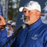 Frank Siller speaking at a Tunnel to Towers Foundation event with microphone and raised hand