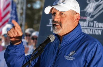Frank Siller speaking at a Tunnel to Towers Foundation event with microphone and raised hand