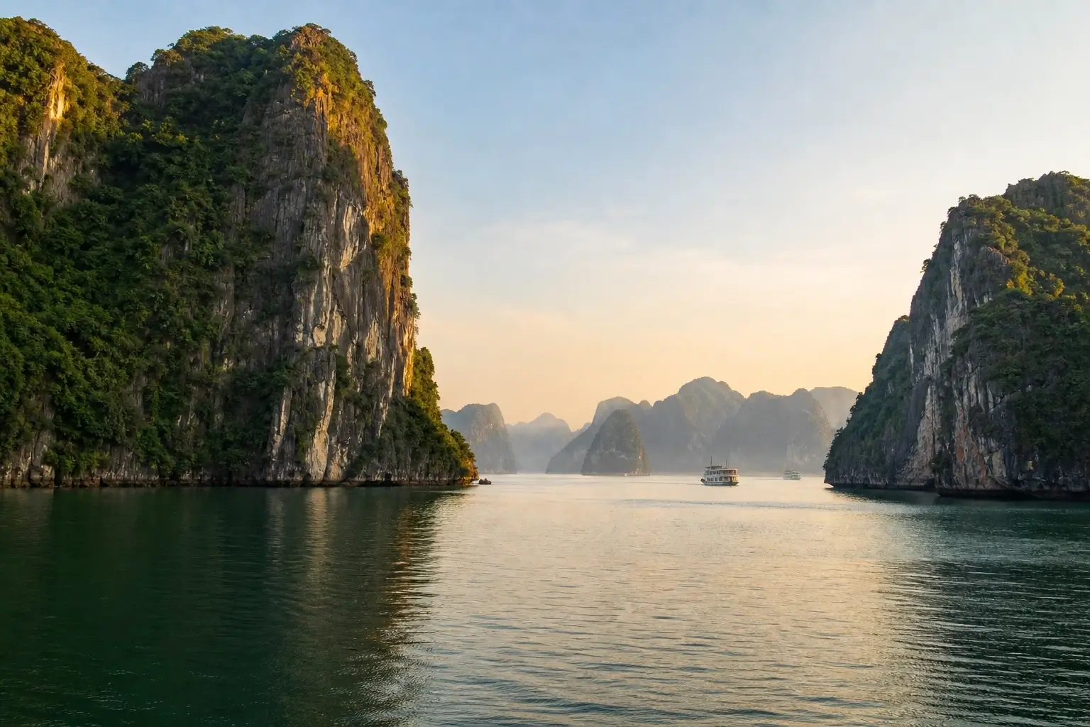 Ha Long Bay limestone karsts at golden hour with cruise boats on calm water