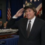 Jack Ford saluting at a Pentagon ceremony beside a USS Gerald R. Ford CVN-78 model.