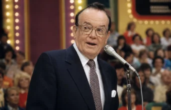 Johnny Olson speaking at a Price Is Right microphone in a vintage TV studio audience setting