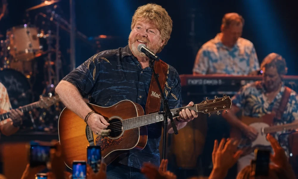 Mac McAnally performs live with acoustic guitar during a tropical concert stage performance