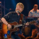 Mac McAnally performs live with acoustic guitar during a tropical concert stage performance