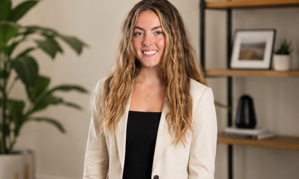 Woman in a cream blazer smiling in a modern office setting for a Mila Volovich creator profile.