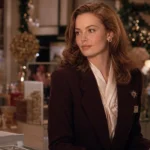 Elegant auburn-haired saleswoman in a burgundy blazer at a festive 1980s department-store counter.
