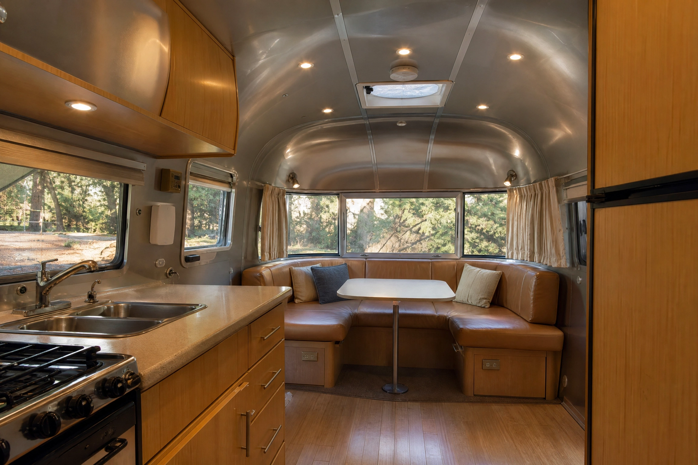 2007 Airstream Bambi 19 interior with aluminum ceiling, galley kitchen, wood cabinets, and booth dinette.