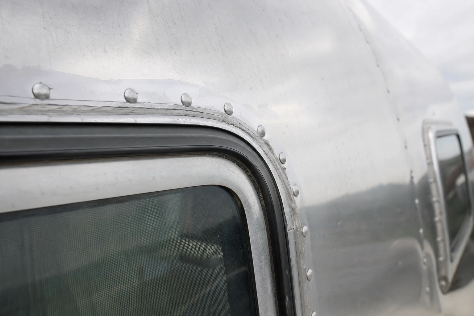 Close-up of Airstream trailer rivets and sealant around an aluminum window seam
