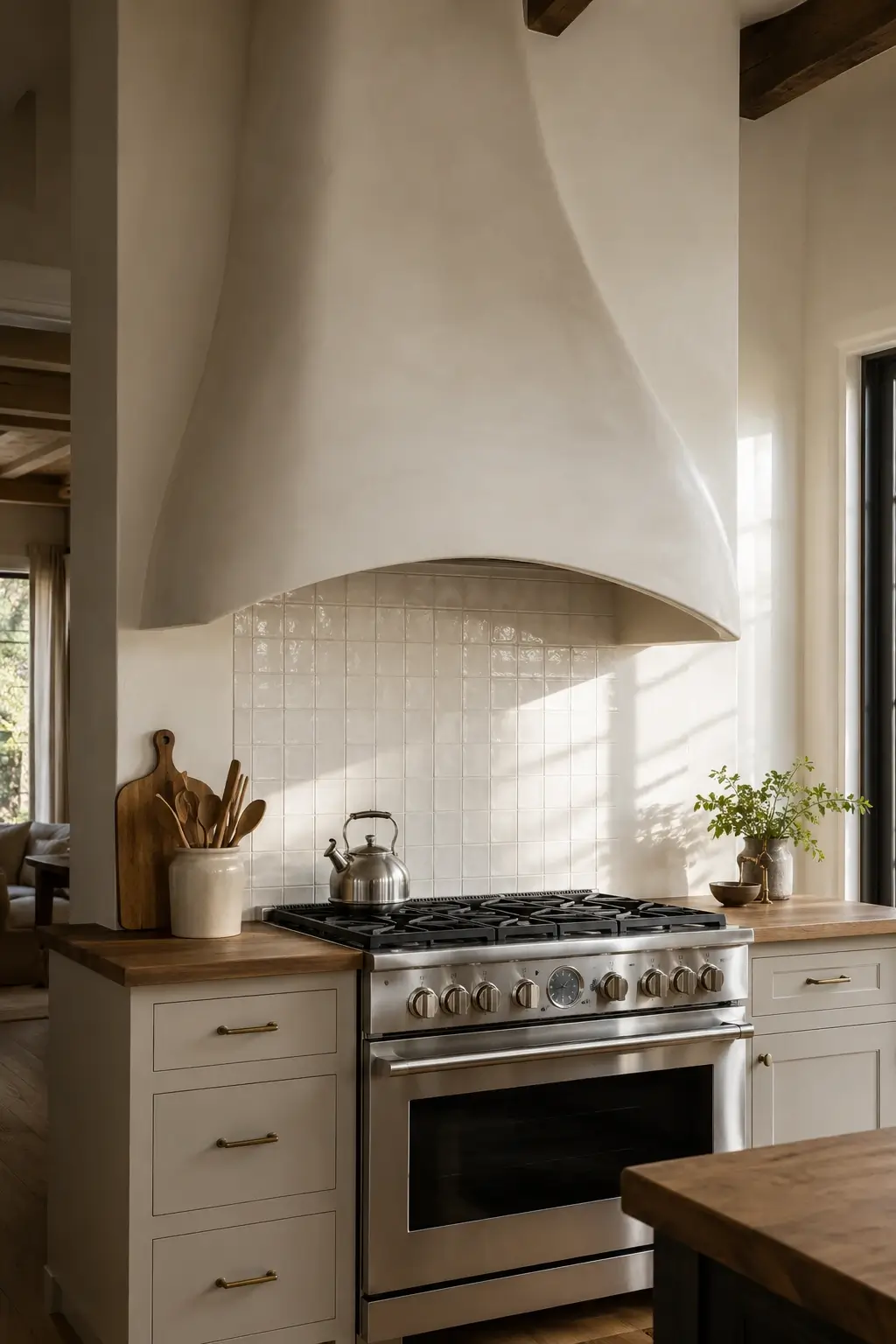 Arched plaster range hood over a stainless stove with cream tile backsplash and warm wood counters.