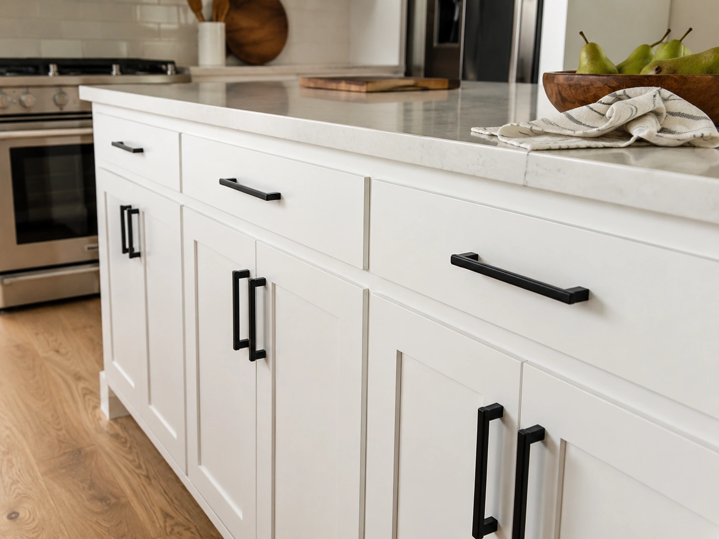 White kitchen island with bold black hardware as the only accent on simple shaker cabinets.