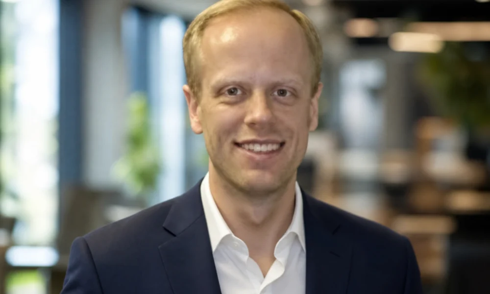 Carl Dvorak professional headshot in a navy suit inside a modern office