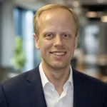 Carl Dvorak professional headshot in a navy suit inside a modern office