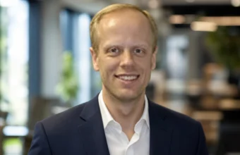 Carl Dvorak professional headshot in a navy suit inside a modern office