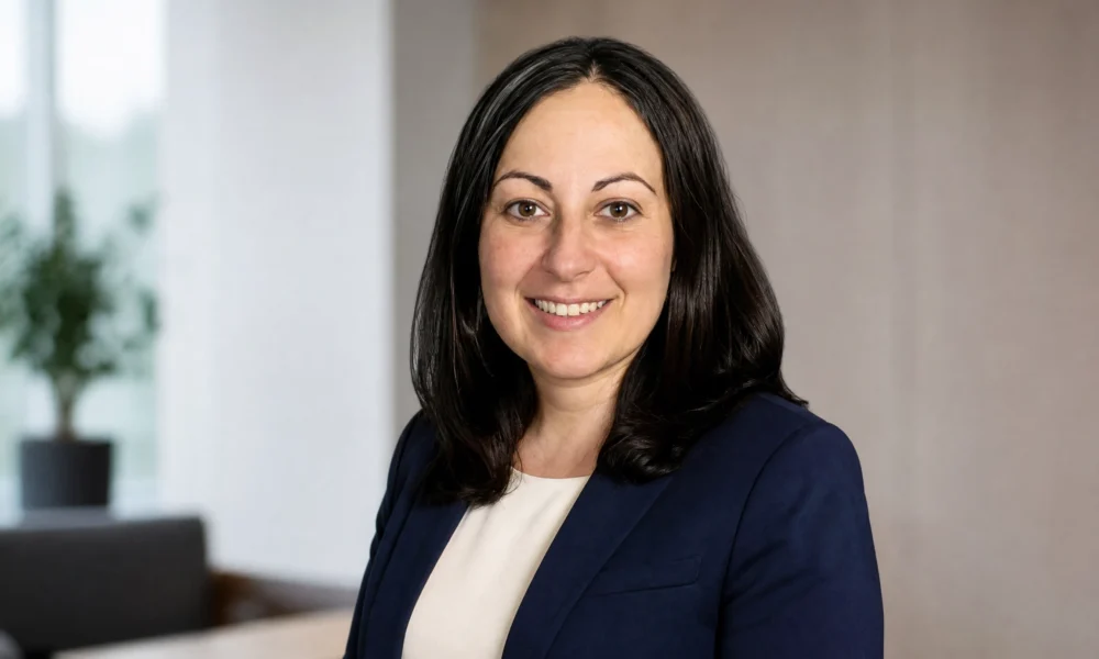 Cheryl Irwin professional portrait in navy blazer in a modern office setting.