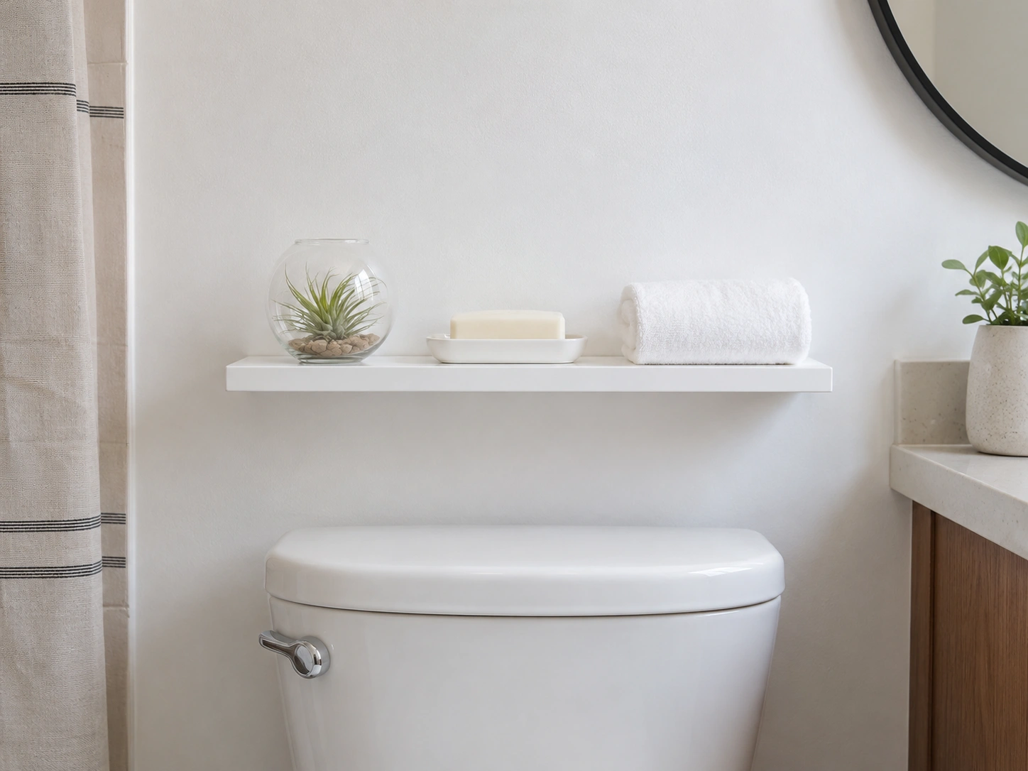 Command strip adhesive shelf above toilet in a renter-friendly small white bathroom.
