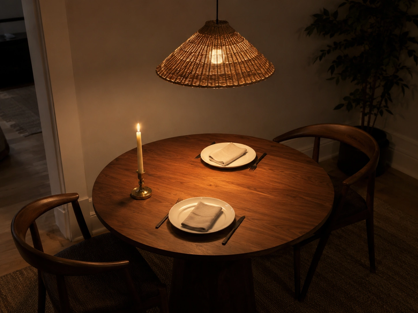 Cozy round dining table with rattan pendant light, candle, and warm evening glow