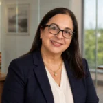 Cristy Garcia professional portrait in navy blazer and glasses