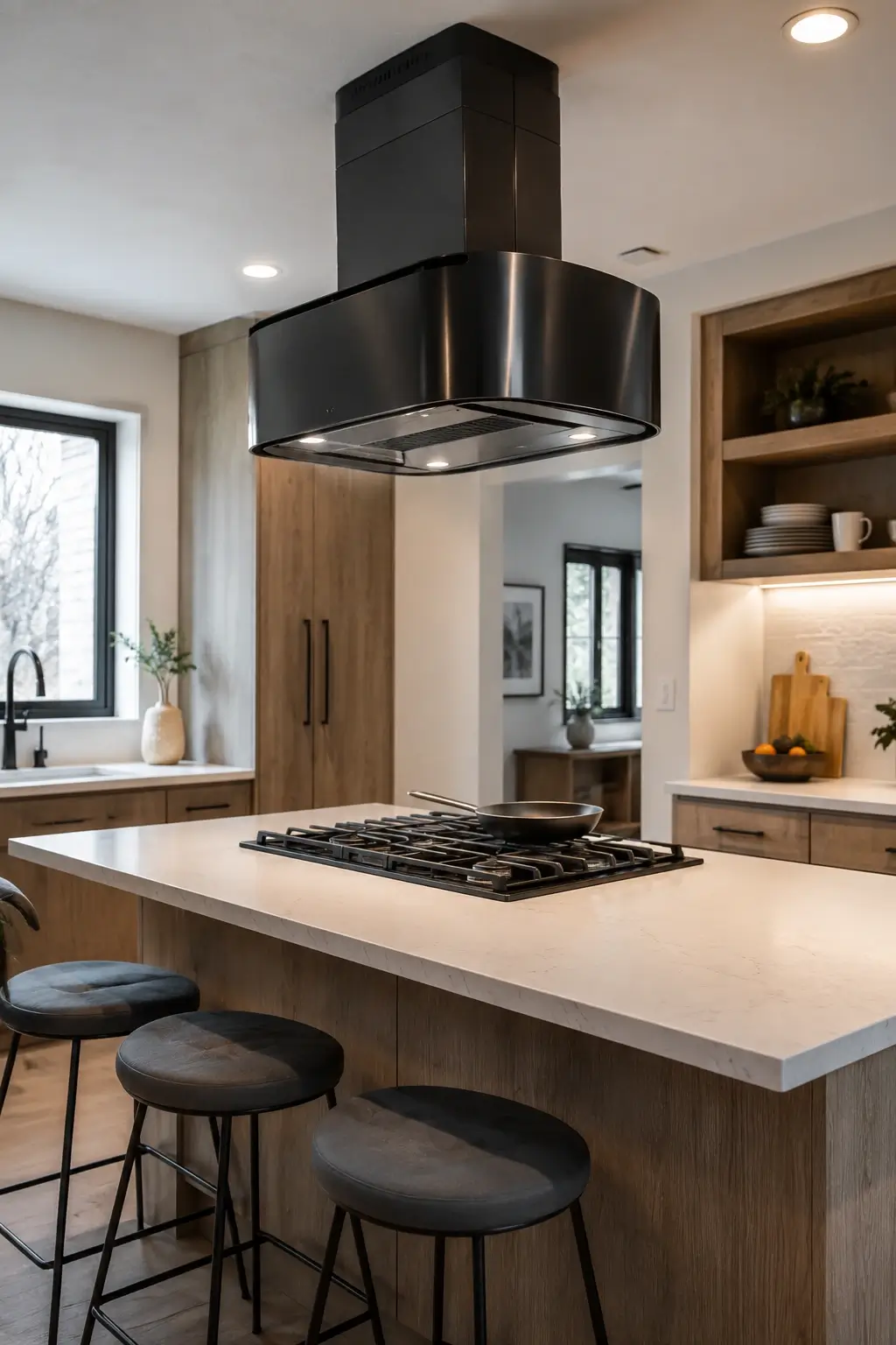 Curved black stainless hood over an island cooktop in a warm modern kitchen.