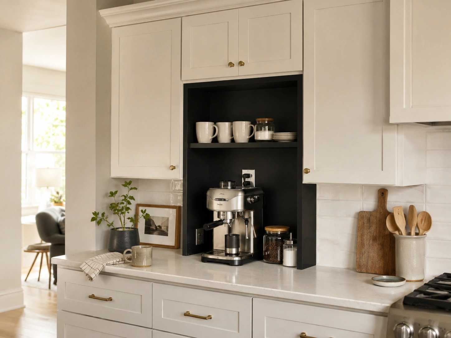 Doorless kitchen cabinet coffee station with espresso machine, mugs, jars, and interior outlet in a white kitchen.