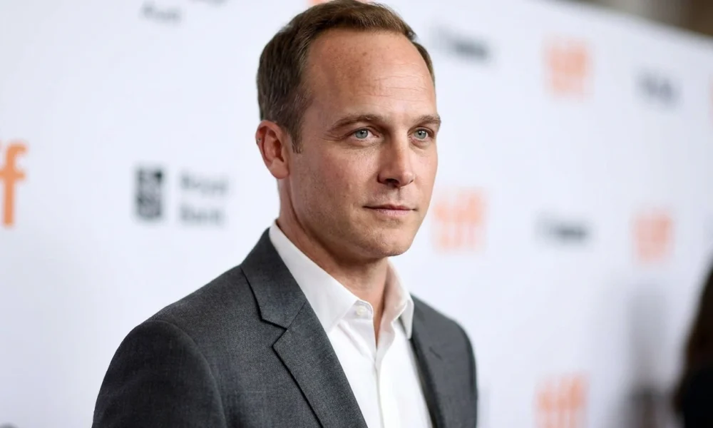 Ethan Embry editorial portrait in a gray blazer at a blurred event backdrop