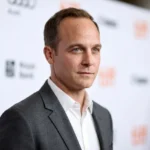 Ethan Embry editorial portrait in a gray blazer at a blurred event backdrop
