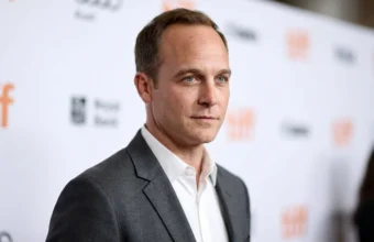 Ethan Embry editorial portrait in a gray blazer at a blurred event backdrop