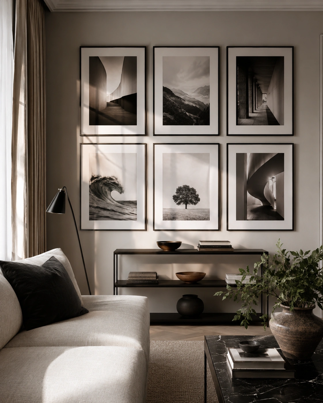 Gallery wall with oversized black frames and monochrome art above a console table in a modern living room.