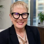 Lorraine Carlson Garavalia smiling in glasses in a professional office setting