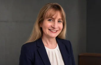 Margot Cleveland smiling in a navy blazer against a gray studio background