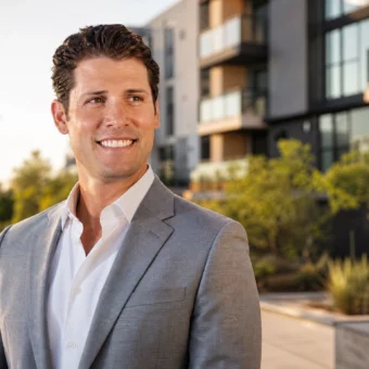 Max Dorsch in a gray suit outside a modern Phoenix apartment complex, reflecting his Taurus real estate career.