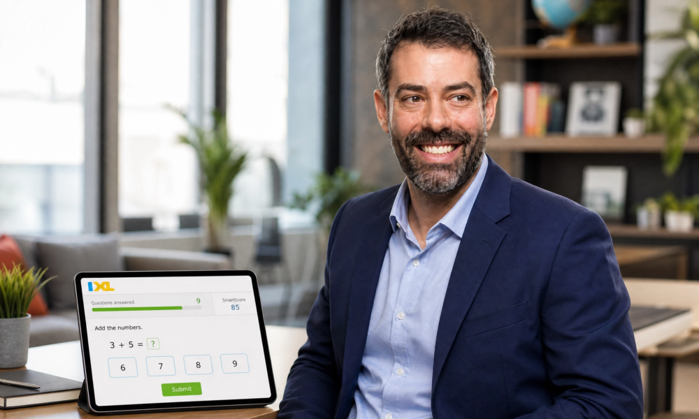 Paul Mishkin seated in an office beside a tablet showing an IXL math question