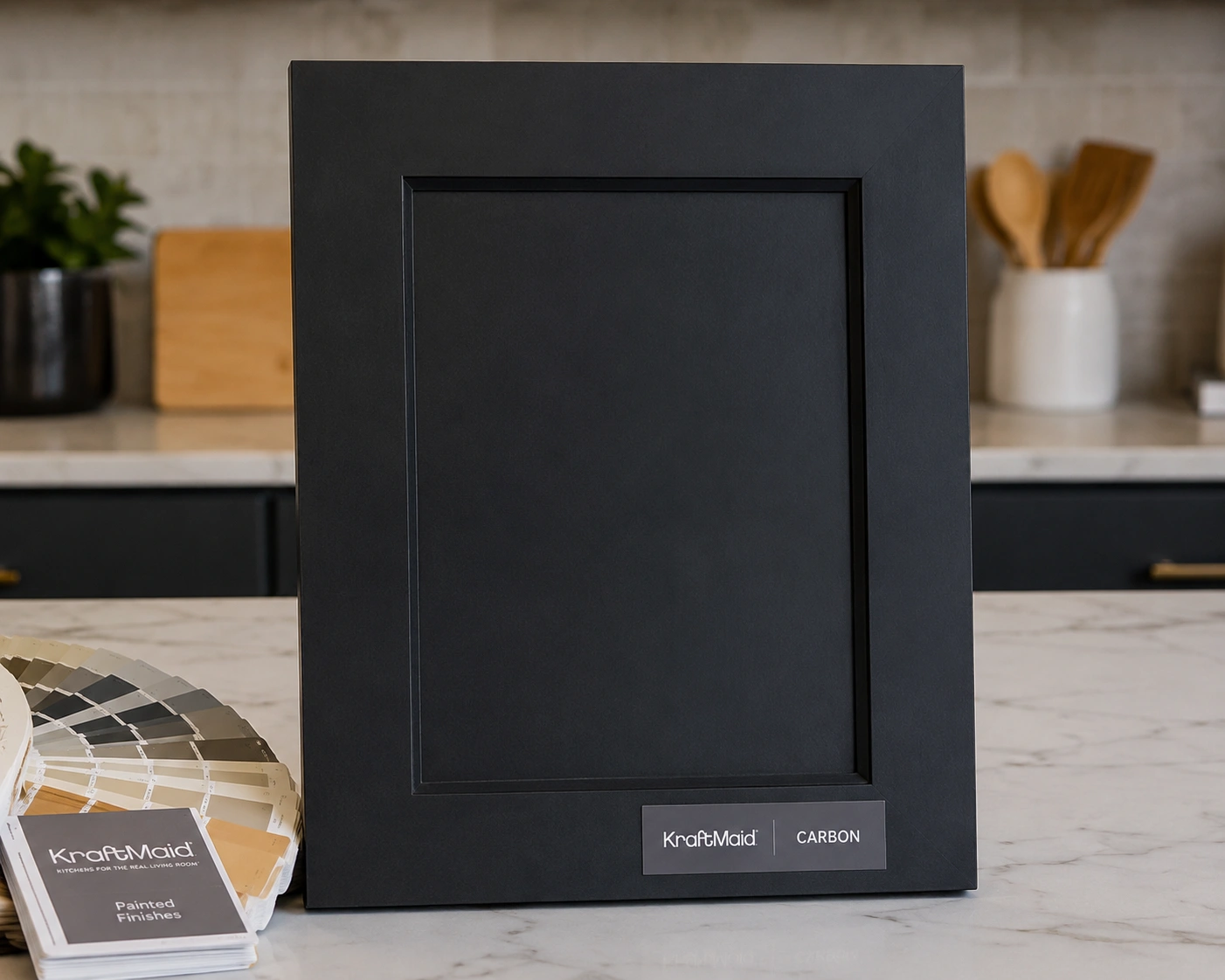 Semi-custom painted black cabinet door sample in a KraftMaid Carbon-style finish on a kitchen counter