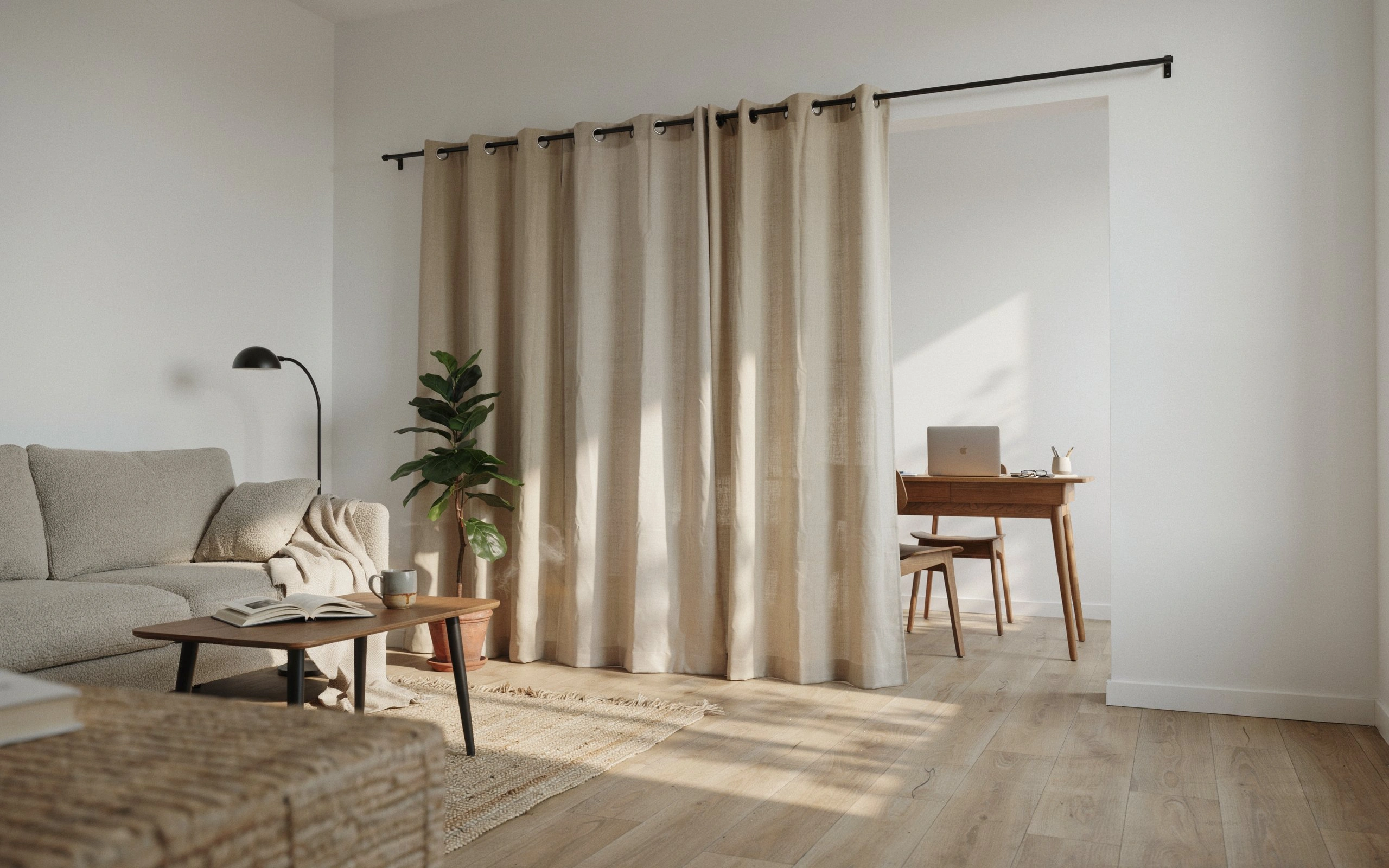 Beige tension-rod curtain divider separating a living room from a small home office.