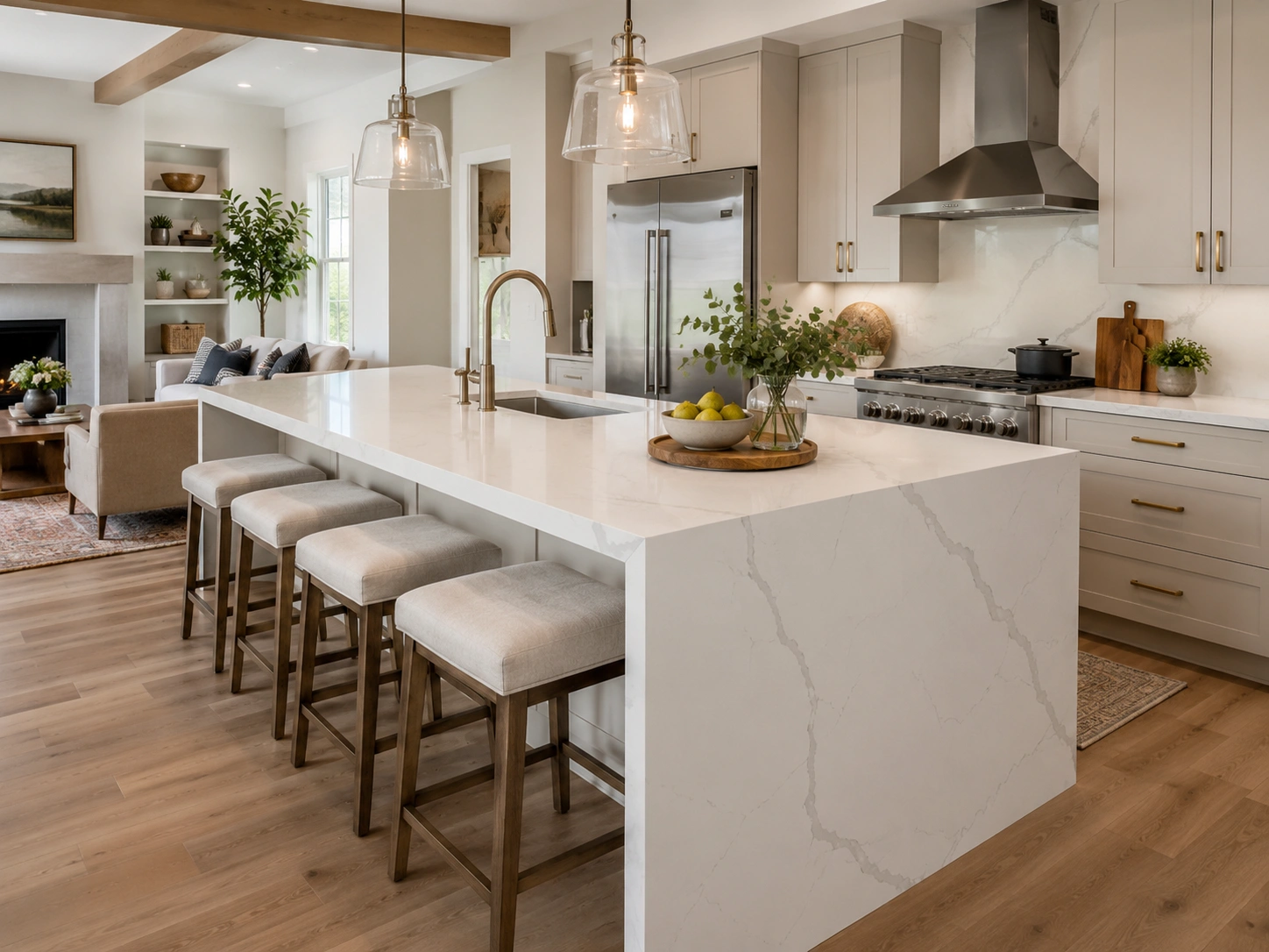 Waterfall quartz countertop island in a modern kitchen with stools, pendant lights, and brass finishes.