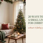 Small living room decorated for Christmas with a slim tree, garland, warm lights, and cozy red and green accents.