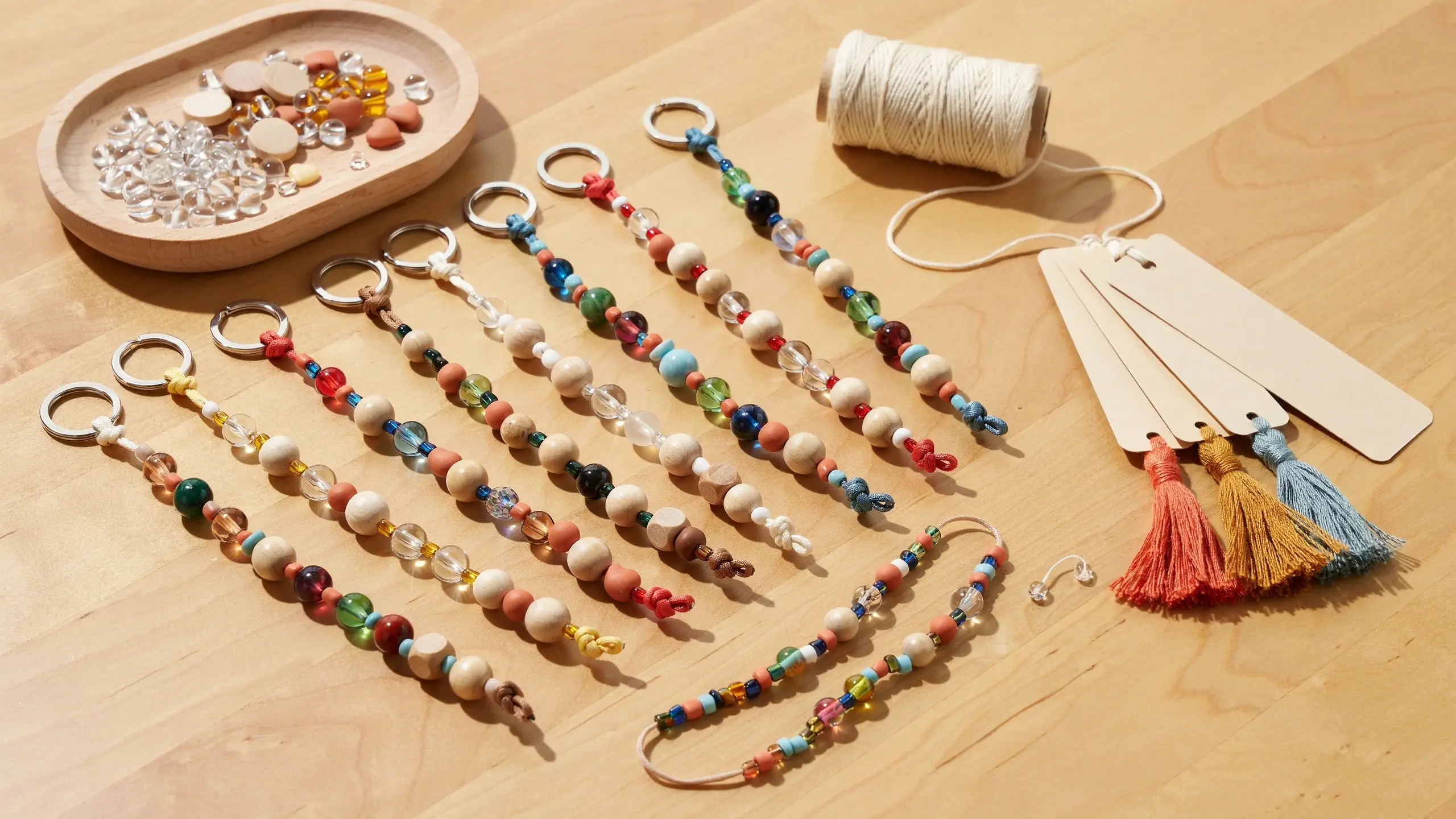 Handmade beaded keychains and bookmark tassels arranged with colorful beads and craft supplies.