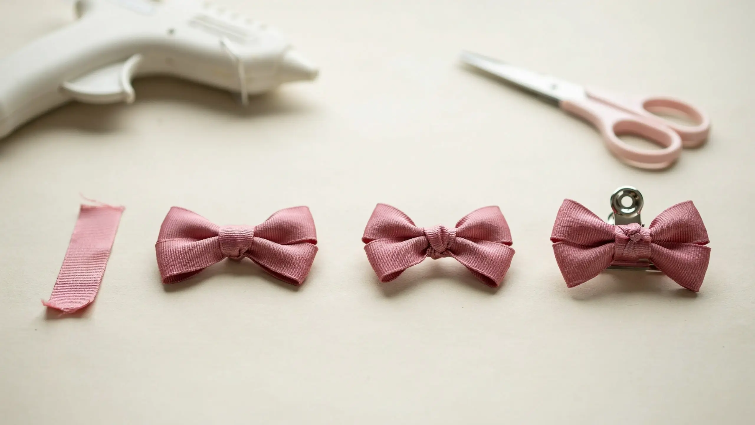 Alt Text: Step-by-step stages of making a classic no-sew pink ribbon bow with a metal hair clip.