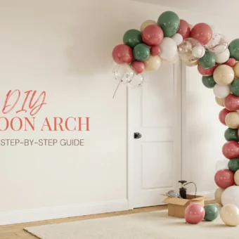 A DIY balloon arch in sage green, dusty rose, and cream colors installed next to a white door in a modern living room, with a balloon pump and supplies on the floor, illustrating an easy step-by-step party decoration tutorial