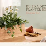 DIY wooden planter box filled with white daisies and trailing ivy for a budget-friendly home decor project under $30.