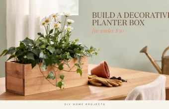 DIY wooden planter box filled with white daisies and trailing ivy for a budget-friendly home decor project under $30.