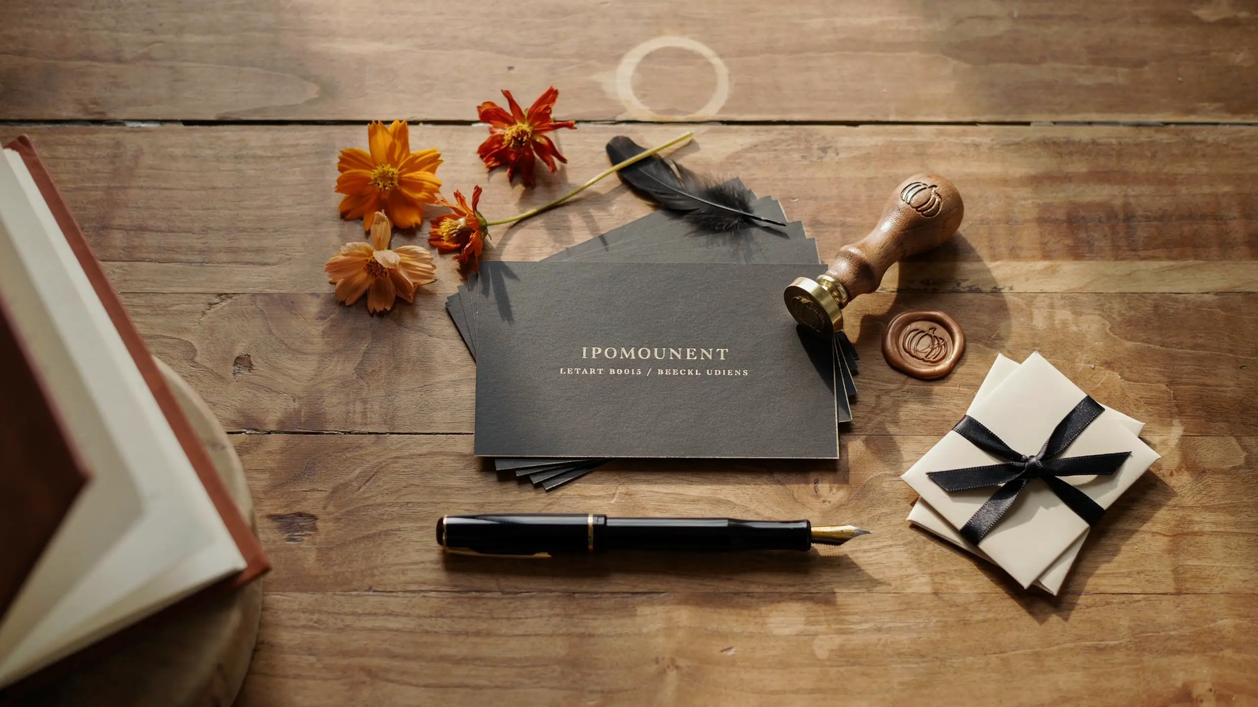 "Luxury dark grey invitation cards arranged on rustic wood with a fountain pen, wooden wax seal stamp, and ribbon-tied white favor boxes."