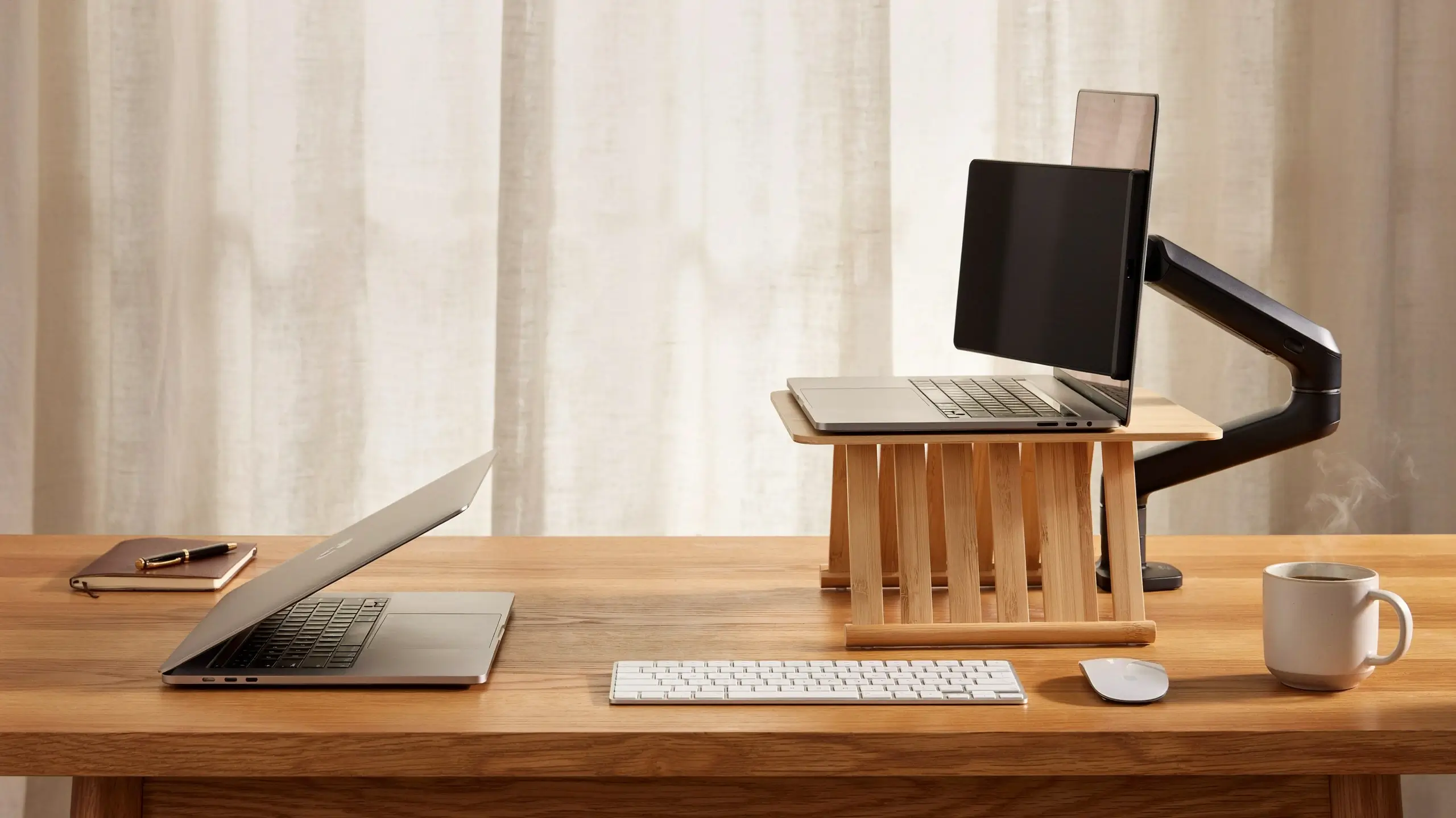 Ergonomic wooden laptop stand and monitor arm setup with wireless keyboard and mouse, designed to promote healthy neck posture in a home office. 