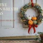 DIY fall pumpkin wreath with small pumpkins and red bow hanging on white door.