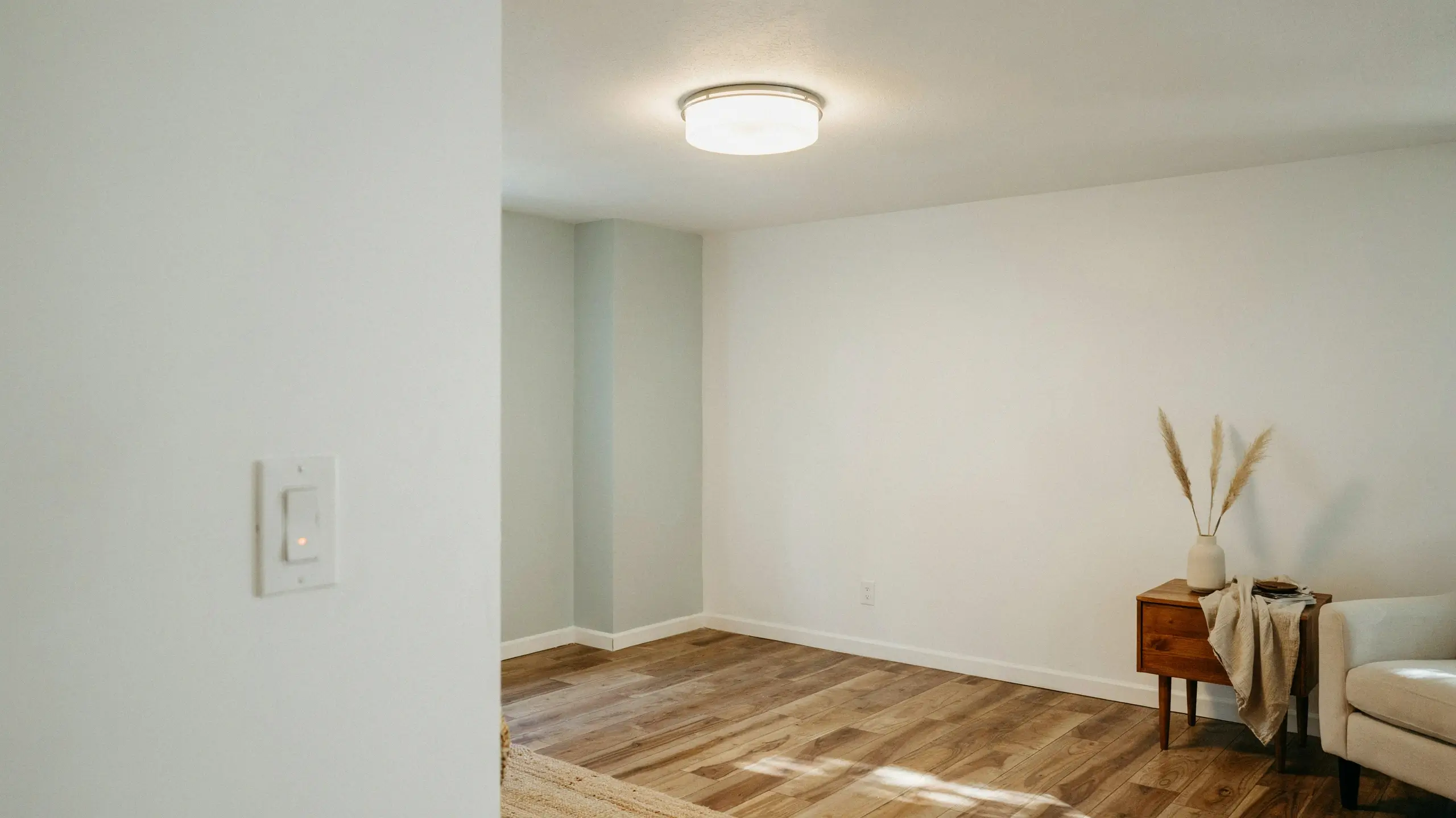 Illuminated white wall light switch successfully powered on and tested, marking the final step of a home electrical restoration project.