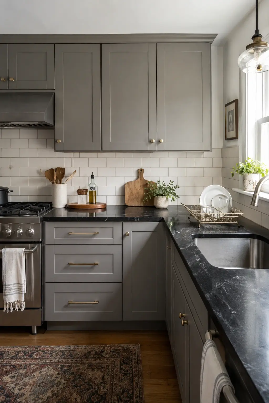 Gray shaker cabinets with white subway tile, warm grout, and black granite countertops in a small kitchen.