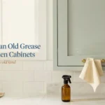 How to clean old grease from kitchen cabinets using a DIY degreasing spray bottle and a soft cleaning cloth, set against a modern subway tile backsplash.