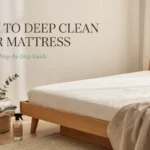 Clean mattress in a bright bedroom with a brush and spray bottle for a step-by-step deep cleaning guide.