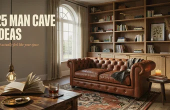 Warm and inviting man cave interior featuring a brown leather tufted Chesterfield sofa, built-in wooden bookshelves, and a rustic coffee table with an open book and a glass of whiskey.